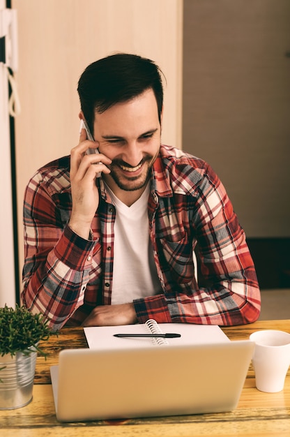 Facet w koszuli za pomocą telefonu i picia kawy