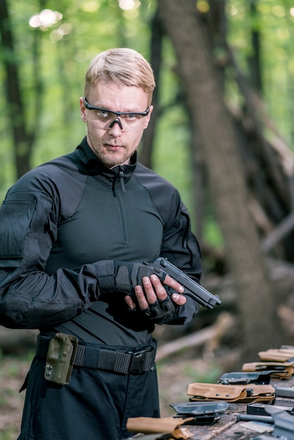 Zdjęcie facet w lesie testuje swoją broń do strzelania do sportu