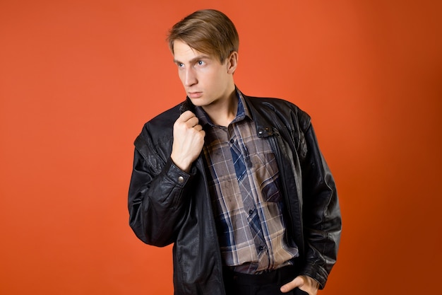 Facet w luźnej koszuli w kratę i skórzanej kurtce, zdjęcie studyjne