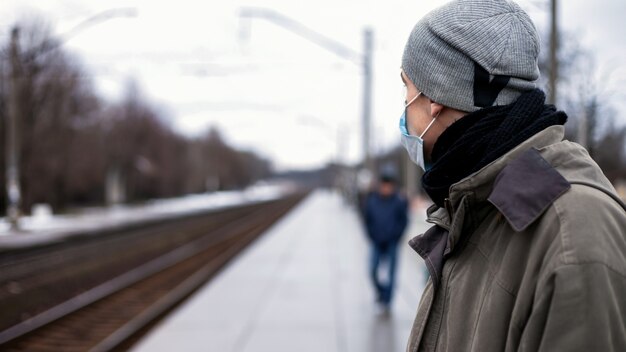 Facet w respiratorze czeka na pociąg. Koncepcja: przeziębienia, grypa, koronawirus
