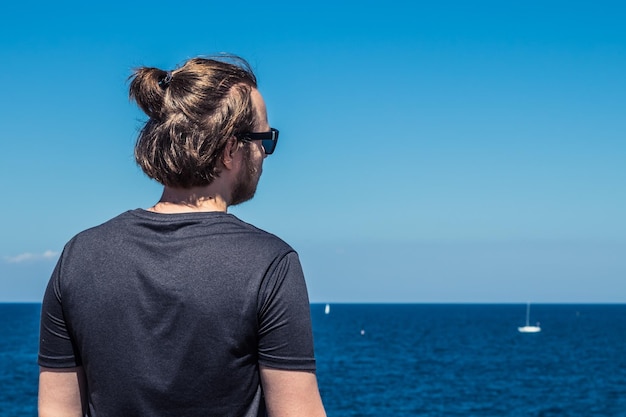 Facet z długimi włosami patrzący na błękitne morze Turystyka koncepcja freelancer i kopia przestrzeń
