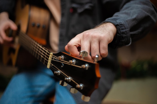 Facet zaciska akord na gitarze akustycznej z zbliżeniem