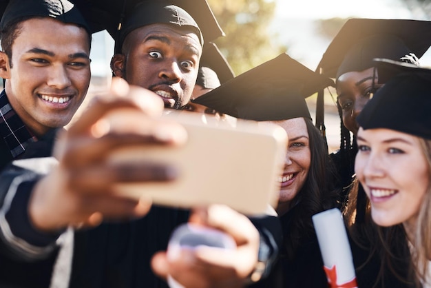 Fajerwerki zaczynają się dzisiaj Ujęcie grupy studentów robiących selfie telefonem komórkowym w dniu ukończenia szkoły