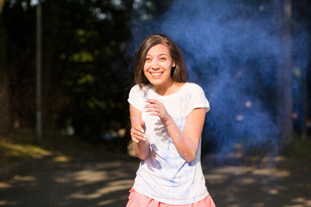 Fajna brunetka azjatycka kobieta bawi się z farbą Holi eksplodującą wokół niej