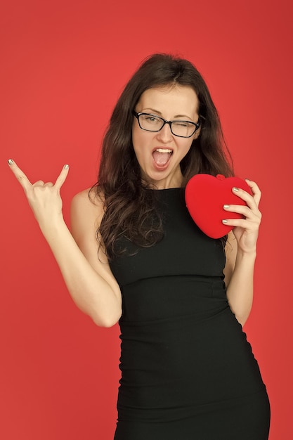 Fajna kobieta w okularach bizneswoman z fajnym rock gestem jego czas imprezy szczęśliwa kobieta uwielbia jej wygląd modę i piękno miłość randka i romans seksowna elegancka kobieta trzyma czerwone serce dnia walentynek