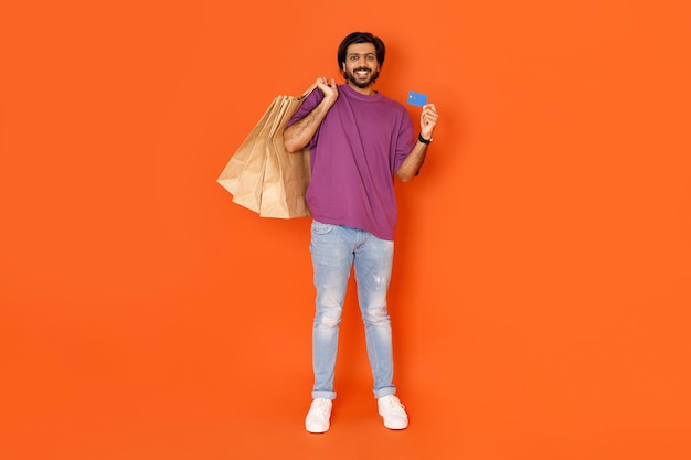 Fajny indyjski facet cieszący się zakupami pokazujący kartę bankową
