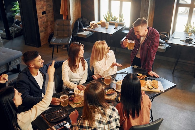 Fajny nastrój Grupa młodych przyjaciół siedzących razem w barze przy piwie?