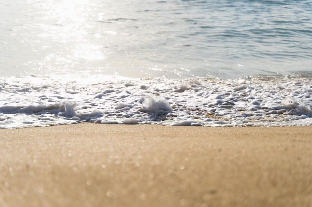 Fala morska przy brzegu na plaży z odbiciem słońca na wodzie Naturalny krajobraz