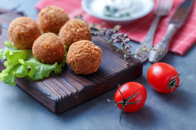 Falafel leży na drewnianej desce do krojenia.