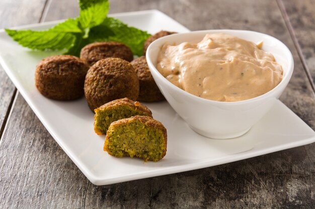 Falafel na talerzu i sosie tahini na drewnianym stole