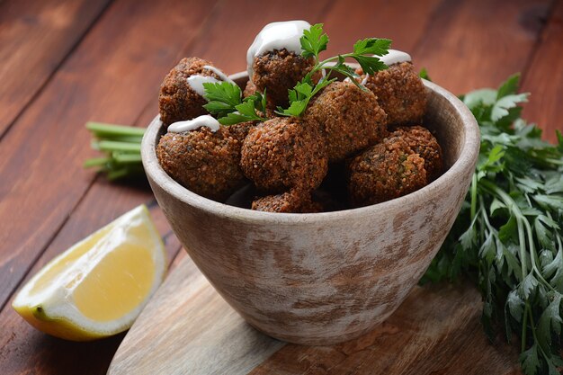 Falafelowe kulki z pietruszką w drewnianej misce z sosem tahini