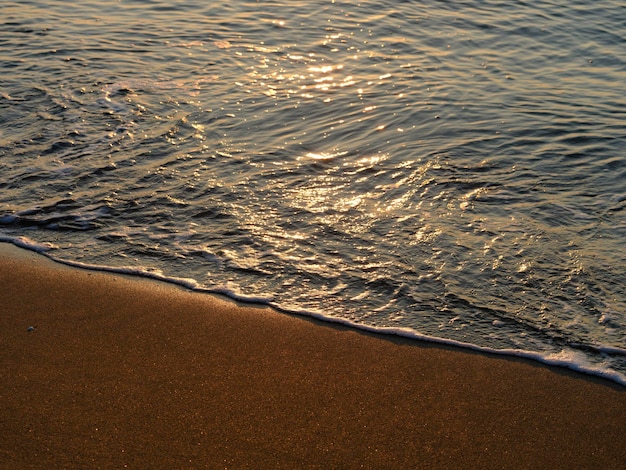 Fale morskie na plaży o zachodzie słońca