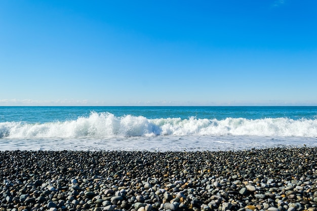 Fale morskie rozbijają się o kamienistą plażę, tworząc rozpryski i rozpryski