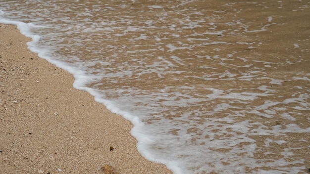 fale na białej, piaszczystej plaży. czysta woda morska. naturalne tło. pływająca piana morska. ocean.