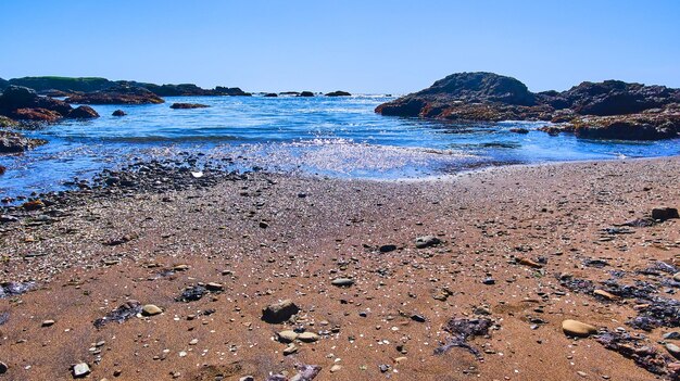 Fale na piaszczystej plaży z błyszczącymi kawałkami szkła