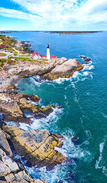 Fale oceanu rozbijają się o skaliste wybrzeże Maine z dużą latarnią morską na krawędzi