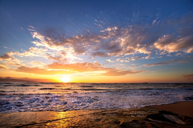 Fale rozbijające się o skały po zachodzie słońca w pobliżu Sunset Beach, Oahu, Hawaje