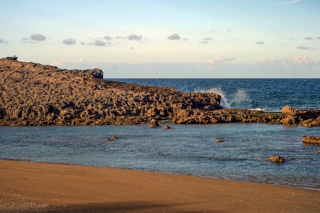 Zdjęcie fale uderzające w iglastą formację skalną na plaży w puerto rico