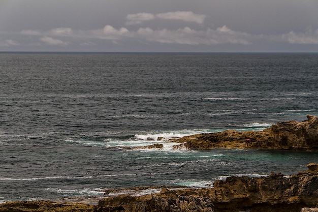 Fale walczą o opustoszałe skaliste wybrzeże Oceanu Atlantyckiego Portugalia