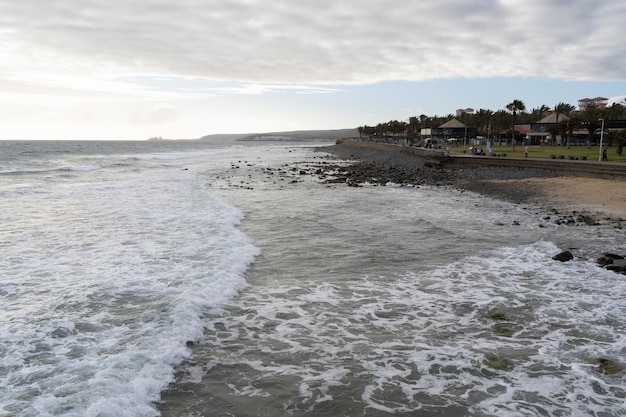 Fale wybrzeża morskiego w pochmurny dzień w Meloneras Gran Canaria Turyści na plaży na Wyspach Kanaryjskich