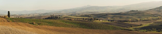 Faliste pola w Toskanii o zachodzie słońca, Włochy. Widok panoramiczny. Naturalny odkryty sezonowy jesień tło.