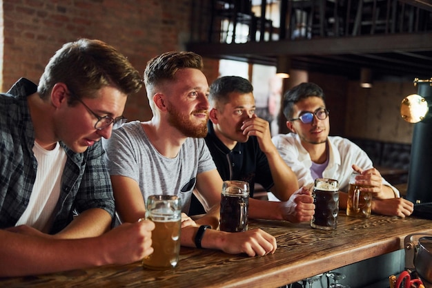 Fani piłki nożnej Ludzie w zwykłych ubraniach siedzący w pubie