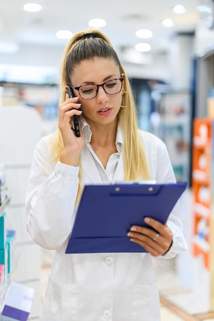 Farmaceuta rozmawia przez telefon z klientem w swoim sklepie