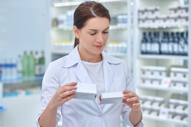Farmaceuta wpatrująca się w pakowane leki farmaceutyczne w swoich rękach