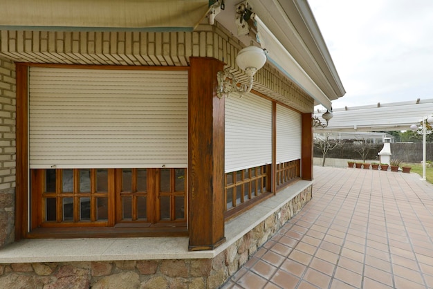Fasada domu jednorodzinnego z zadaszoną drewnianą werandą i brązowymi podłogami z lastryko