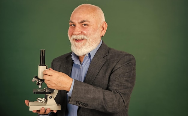 Fascynująca lekcja biologii szczęśliwy starszy nauczyciel używa chemii mikroskopu w szkole laboratorium eksperymenty naukowe z mikroskopem w laboratorium sprzęt laboratoryjny szkoły biologii człowiek w klasie tablica