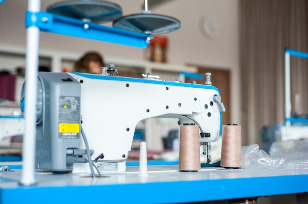Zdjęcie fashion design studio wisząca maszyna do szycia ubrań i różne przedmioty związane z szyciem na stole