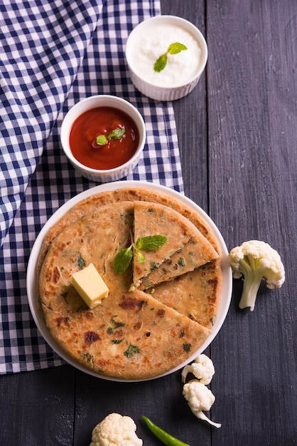 Zdjęcie faszerowany kalafior lub gobi paratha to indyjski flatbread. ulubione menu śniadaniowe lub lunchowe w północnych indiach, podawane na nastrojowym tle z twarogiem i ketchupem w misce