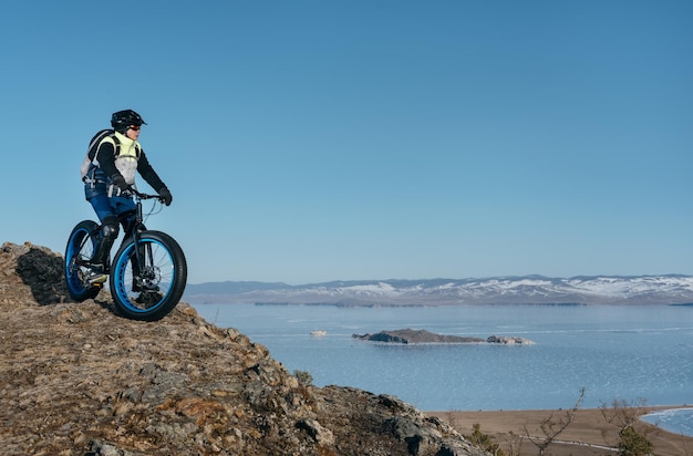 Fatbike (zwany także fat bike lub fat-tire bike) - Jazda na rowerze na dużych kołach. Nastolatek jeździ na rowerze przez śnieżne góry w tle.