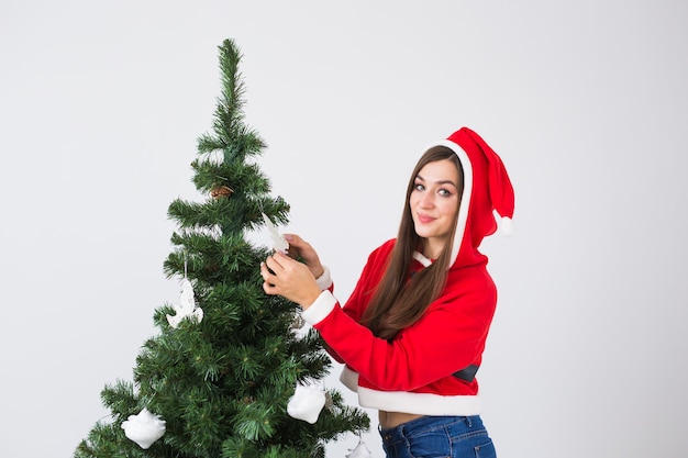Ferie zimowe, święta Bożego Narodzenia i koncepcja ludzi - Piękna młoda kobieta dekorująca choinkę w