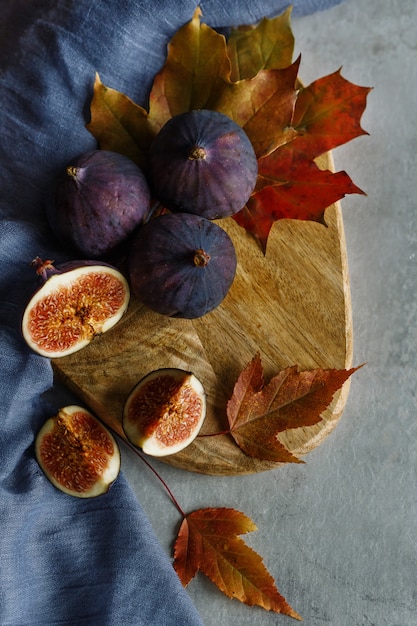 Figi I Plastry Fig Z Jesiennymi Liśćmi Na Drewnianej Desce Do Krojenia. Niebieski Materiał.