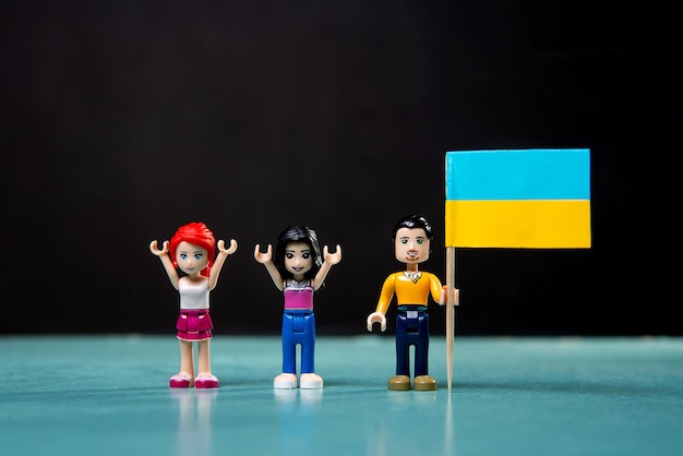 Figurki Lego z ukraińską flagą w dłoniach na czarnym tle koncepcja rajdu w kraju przeciwko wojnie i agresji Rosji 24022022xA
