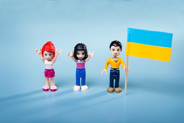 Figurki Lego z ukraińską flagą w dłoniach na niebieskim tle koncepcja rajdu w kraju przeciwko wojnie i agresji Rosji 24022022xA