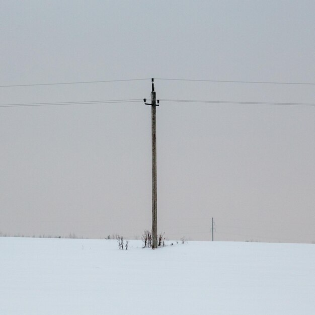 Zdjęcie filar elektryczny na pokrytym śniegiem polu na tle nieba