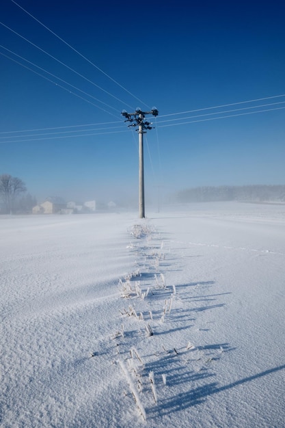 Zdjęcie filar elektryczny na pokrytym śniegiem polu na tle nieba