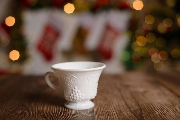 Filiżanka białej herbaty z wytłoczonym grawerowaniem na drewnianym stole z bożonarodzeniowym tłem