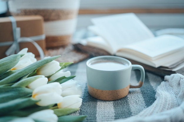 Filiżanka cappuccino bukiet tulipanów otwarta książka i prezent dzień dobry estetyka