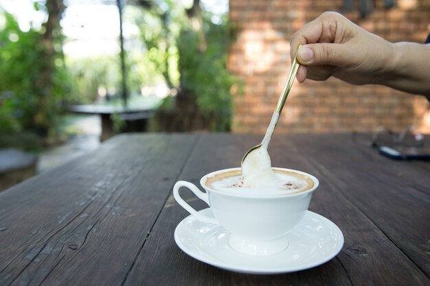 Filiżanka cappuccino z latte art na drewnianym stole. Piękne piankowe, zielone kubki ceramiczne, stylowe tonowanie