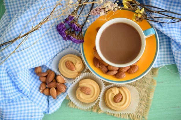 Filiżanka cukierniany latte i ciastko z migdałami na drewnianym stole.