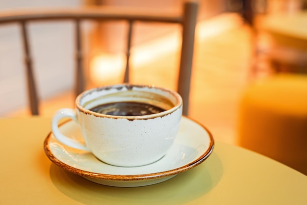 filiżanka czarnej kawy na talerzu na krawędzi stołu w przestrzeni kopiowania kawiarni