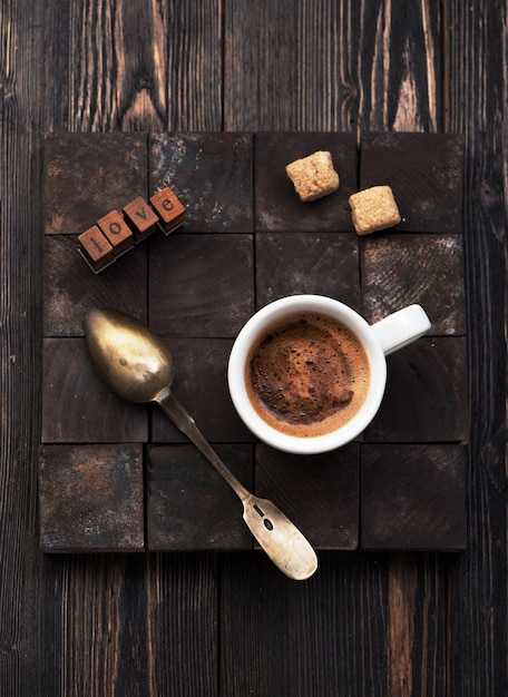 Filiżanka czarnej kawy z cukrem na drewnianym tle i tekst miłosny, flat lay