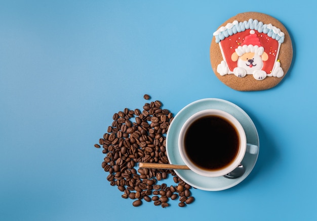 Filiżanka czarnej kawy, ziaren kawy i piernika na niebieskim tle, miejsce na tekst. Koncepcja Bożego Narodzenia.