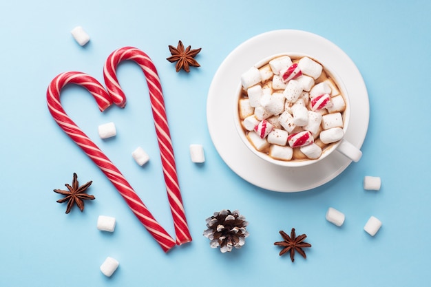 Filiżanka gorąca czekolada z marshmallow kakaowym proszkiem i karmelem na pastelowym błękitnym tle z kopii przestrzenią. Koncepcja Bożego Narodzenia zima.