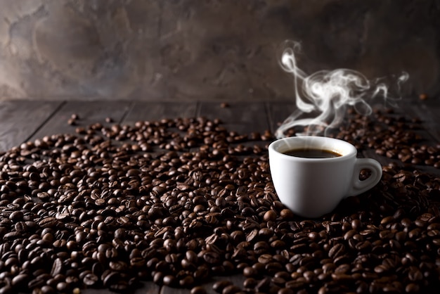 Filiżanka gorąca kawa na tle kaw adra na ciemnym drewnianym tle