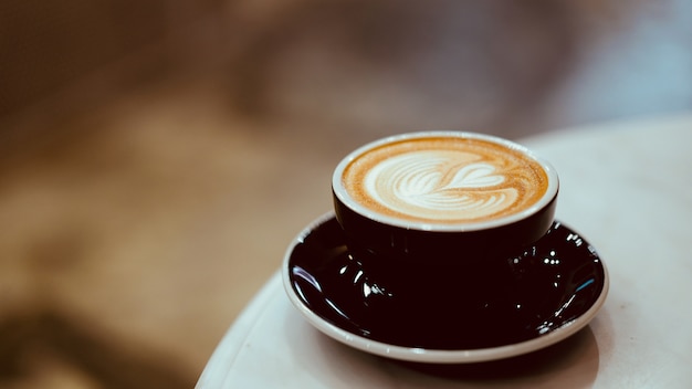 Filiżanka gorącej kawy latte z latte art w kształcie serca, koncepcja miłośnika kawy
