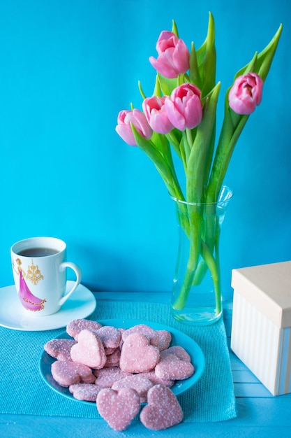Zdjęcie filiżanka herbaty i różowe ciasteczka tulipany 8 marca selektywne skupienie